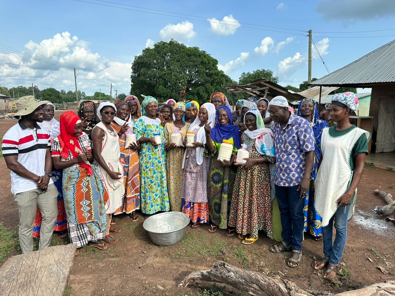 Women cooperative members holding jars of processed shea butter in their community